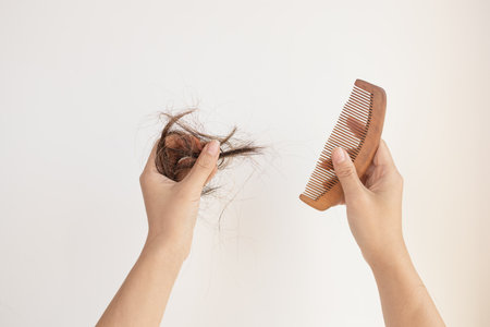 Females hands clean the comb from fallen hair. close up. white background. Concept of hair loss,...