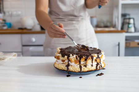 House wife making finishing touches for birthday chocolate cake dessert. A woman makes a homemade...