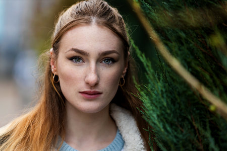 Close up portrait of young beautiful fashionable redhead woman with freckles, long hair, wearing...