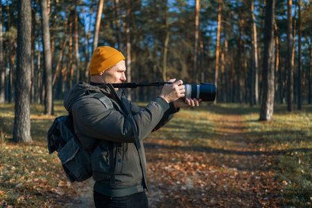 Young photographer taking photo in the forest. photographer with big professional camera.