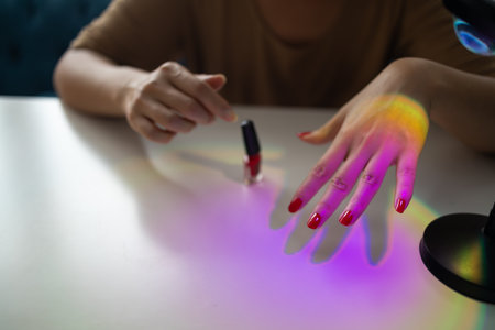 Woman paints her nails with red polish herself at home. Manicured red nailsの写真素材