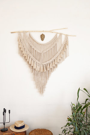 Stylish and modern living room interior in boho style with mockup photo frames, beige macrame and...