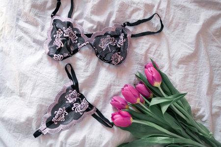 Lace lingerie on bed background with flowers, top view.の写真素材