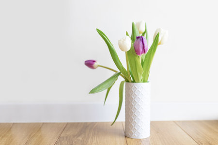 Fresh pink tulip bouquet on a shelf in front of a white wall. view with copy spaceの写真素材