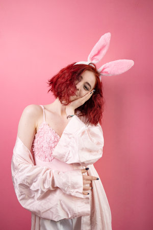 Lovely beautiful young woman posing in sensual pink lingerie and bunny ears. pink background. studio shot.の写真素材