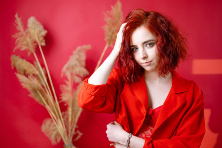 Fashionable young woman in a red suit. red background.の写真素材