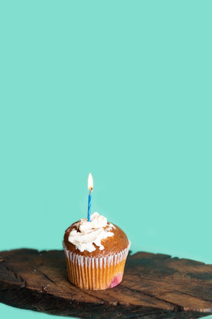tasty birthday cupcake with one candle, on blue background.の写真素材