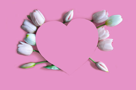 Frame of tulips, branches, leaves on pink background. Flat lay, top view. Collage with paper hearts...