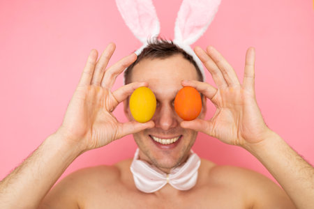 Portrait of a muscular man with rabbit ears posing isolated on a pink background