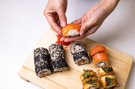 Close-up of chef's hands preparing Japanese food. Japanese chef prepares sushi in a restaurant. A young chef prepares traditional Japanese sushi on a cutting board.の写真素材