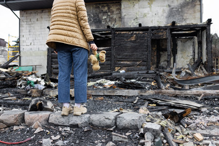 A girl next to a house destroyed by the war. War in Ukraine. Ukrainian refugees. Child in the ruins of his house destroyed by the war. peace conceptの写真素材