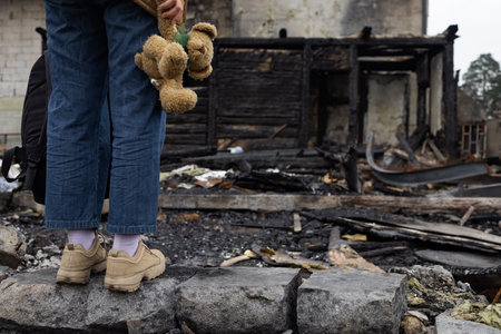 A girl next to a house destroyed by the war. War in Ukraine. Ukrainian refugees. Child in the ruins of his house destroyed by the war. peace conceptの写真素材