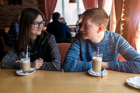 Happy couple talking and having fun together at bar cafeteria. lifestyle concept with young people on positive mood drinking latte.の写真素材