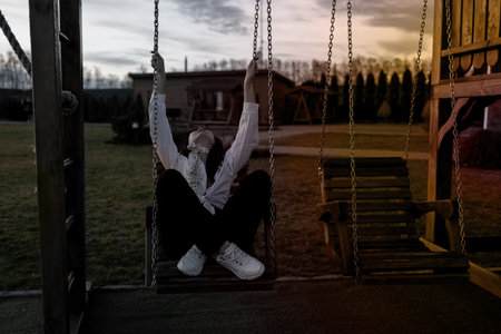 Young sad asian woman sitting on a swing in the evening.の写真素材
