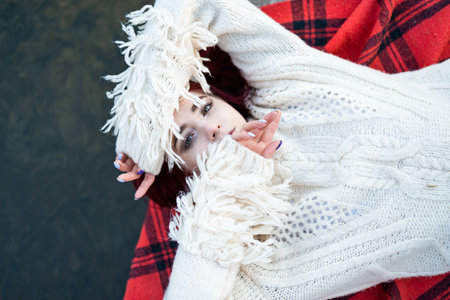 Relaxed Redhaired girl in sweater lying on a pier by natureal lake in autumn.の写真素材