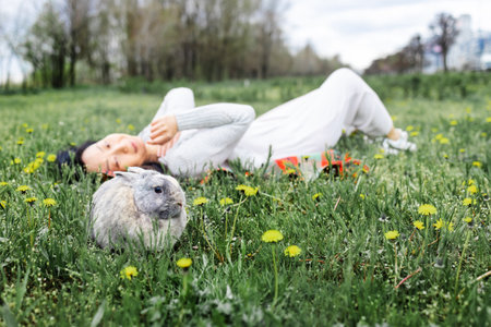 Asian woman holding Lovely bunny easter fluffy rabbits on green field. The Easter hares.の写真素材