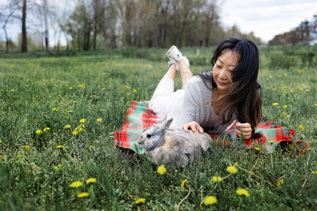 Asian woman holding Lovely bunny easter fluffy rabbits on green field. The Easter hares.の写真素材
