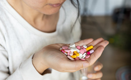 Unrecognizable woman in one hand handful of tablets, in other glass of clean water close up. lot of...