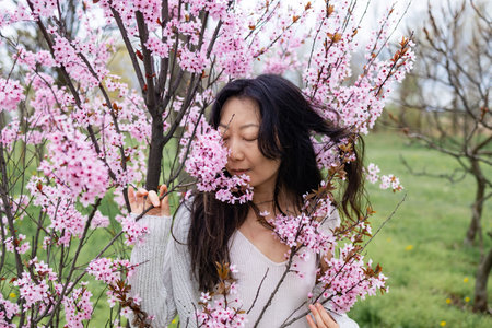 spring girl face. Close up portrait of tender asian woman at sakura flowers background. Hanami...