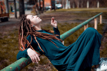 young pretty girl teenage with dreadlocks outside smoking cigarette, looking like real junky, social...