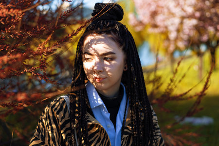 Young tender brunette girl with dreadlocks near herbal branch in front of her face. Portrait of a...