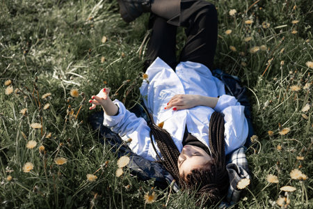 Relaxing woman lying on spring blooming meadow. Girl resting in summer park. Enjoy life, having fun, leisure, relaxation, springtime, lifestyle conceptの写真素材