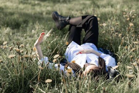 Relaxing woman lying on spring blooming meadow. Girl resting in summer park. Enjoy life, having fun,...