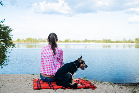 dog and woman at the lake. Female person and her pet dog sit together and enjoy beautiful sight...