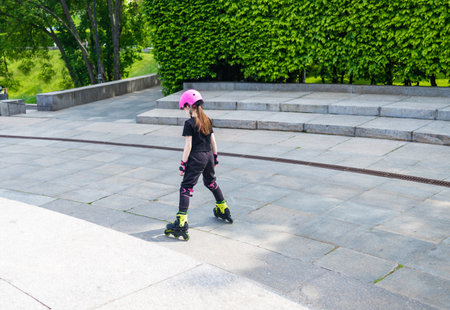 Child on inline skates in park. Kids learn to skate roller blades. Little girl skating on sunny...
