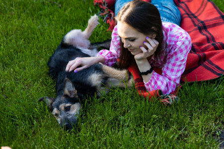 Beautiful young woman playing with her young dog in the park outdoors. life style portrait.の写真素材
