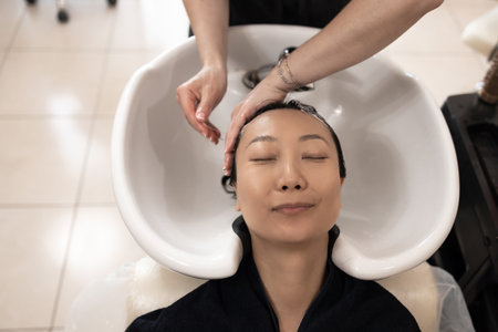 Beautiful asian woman getting a hair wash at the barbershopの写真素材