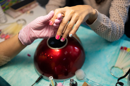 Nail care and manicure. Close-up of beautiful female hands Applying transparent nail polish on healthy natural nails of a woman in a beauty salon. Manicurist hand painting client'sの写真素材