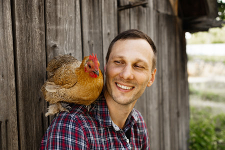 The farmer hugs a chicken. pleasant man is hugging a cock. close up shot emotions.の写真素材