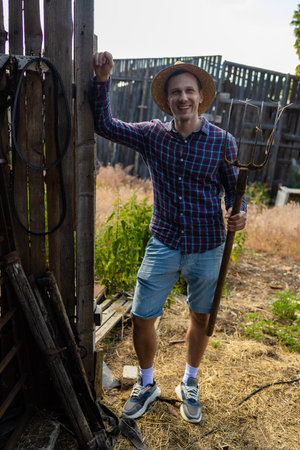Portrait of happy farmer leaning on cowshed doorの写真素材