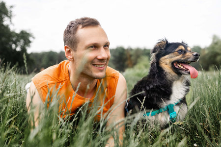 Young man with his dog in the meadow on a sunny dayの写真素材