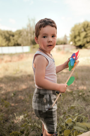 Little boy plays in the garden, a child stands in the open air and looking at camera. Kid's vacation in summer concept.の写真素材