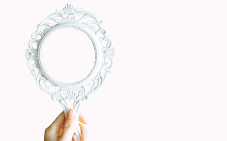 Hand holding antique mirror isolated on white background. Copy space for text.の写真素材