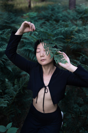 Romantic portrait of an asian woman in a fern in the forest. Art woman natural makeup resting in nature. green fern thicketsの写真素材