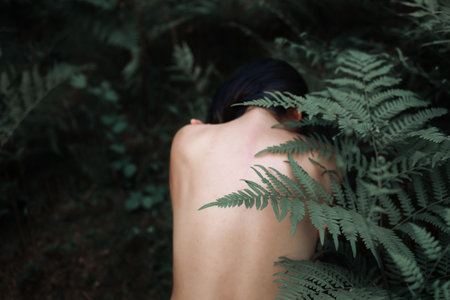 Young woman with fern leaves in the forest. back view.の写真素材
