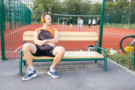 Young man sitting on a bench and listening to music with headphones.の写真素材