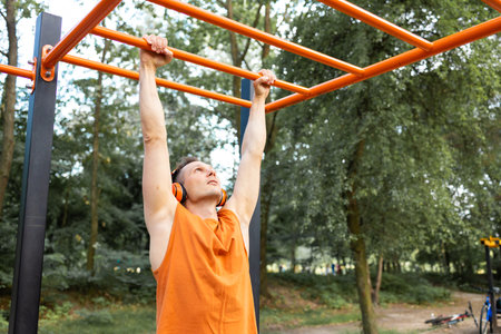 Young man doing pull-ups on a horizontal bar in the park