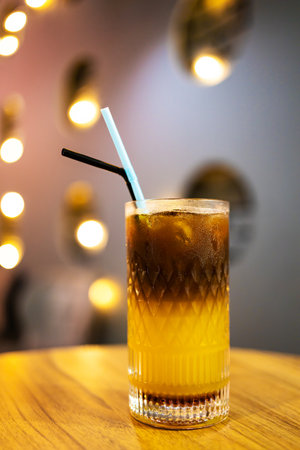 Cocktail with ice cubes on a wooden table in a bar