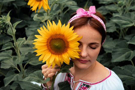 Beautiful young woman with sunflower in a field of sunflowers