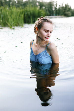 Young beautiful girl in a blue swimsuit on the river bank.の写真素材