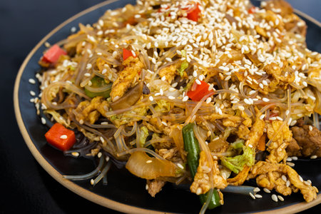 Stir-fried rice noodles with chicken, vegetables and sesame seedsの写真素材