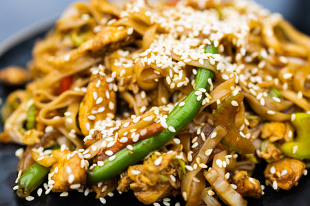Stir-fried noodles with chicken, vegetables and sesame seedsの写真素材