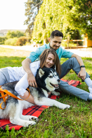 Young couple in love with siberian husky dog in summer parkの写真素材