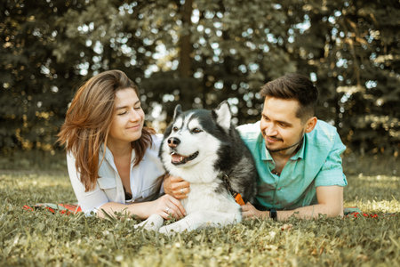 Happy young couple with a dog in the park on a summer dayの写真素材