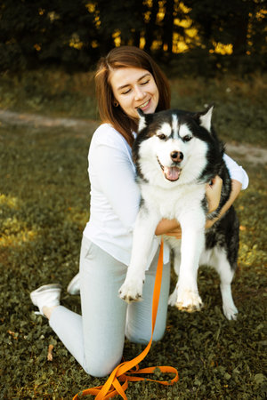 Young woman with her dog husky in the park at sunset.の写真素材