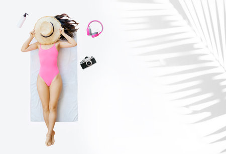 Beautiful asian woman in pink swimsuit and hat lying on white background.の写真素材